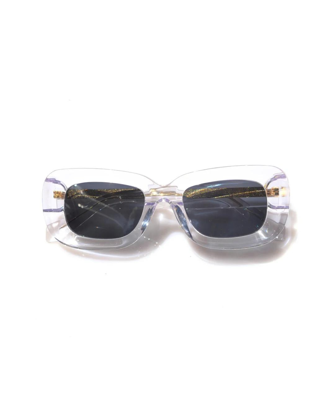 Front view of Rewrites Limited Edition Unfazed Sunglasses. Handcrafted in Italy from Mazzucchelli acetate, featuring a rectangular shape, sturdy fit, and unisex design with a thick transparent frame and grey see-through lens with scratch-resistant coating.