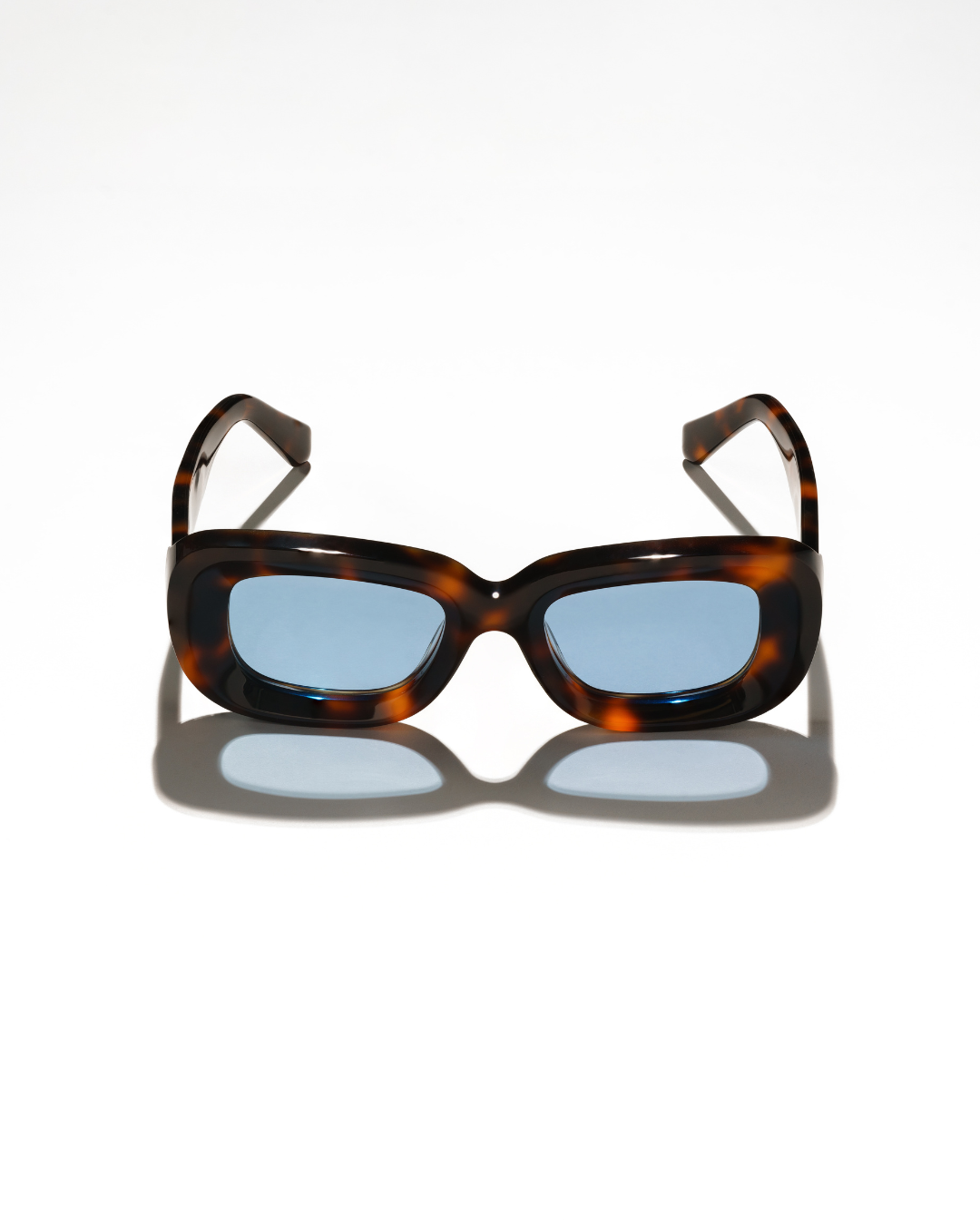 Front view of Rewrites Limited Edition Unfazed Sunglasses. Handcrafted in Italy from Mazzucchelli acetate, featuring a rectangular shape and sturdy fit. The unisex design includes thick tortoiseshell frames and blue see-through lenses with a scratch-resistant coating.